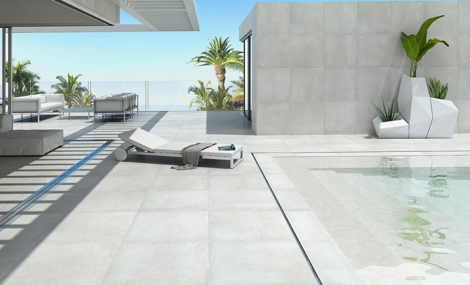 a pool deck and and accent wall behind it with very light color porcelain tile